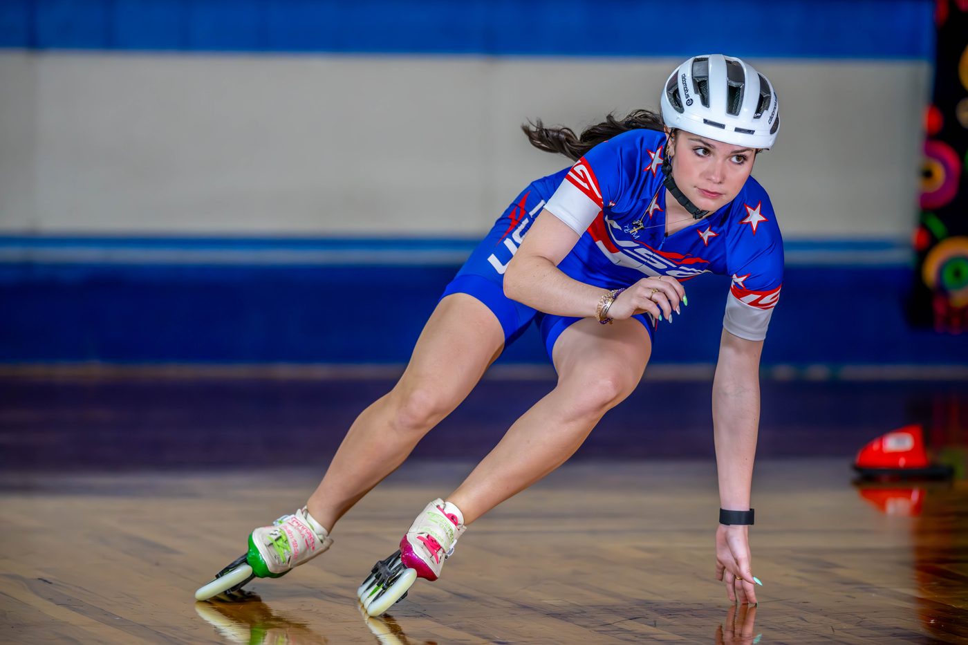 A competitive inline speed skater in a Team USA uniform leaning into a turn, shot by a real working sports photographer