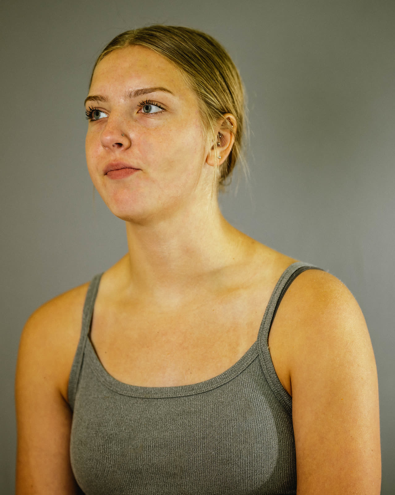 A studio portrait of a young woman against a grey backdrop, shot by a real working photographer